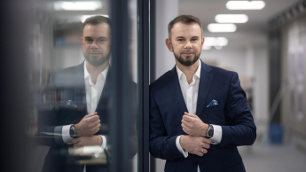 Zarządzanie jakością w branży automotive | Studia podyplomowe w Bydgoszczy | Uniwersytet WSB Merito Bydgoszcz: Główna grafika: Toruń - studia podyplomowe - Uczestnik studiów podyplomowych pozujący do zdjęcia z odbiciem w oknie