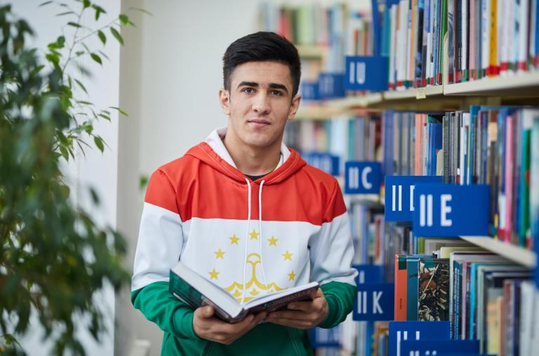 Biblioteka | Uniwersytet WSB Merito Bydgoszcz: student przegląda książkę w bibliotece Uniwersytetu WSB Merito Bydgoszcz