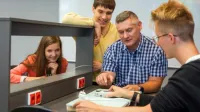 Logistics of Trade and Distribution | Uniwersytet WSB Merito Chorzów: studenci omawiający użycie urządzenia