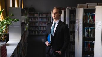 Zarządzanie finansami w biznesie | Studia II stopnia ze studiami podyplomowymi  | Uniwersytet WSB Merito Chorzów: Student stojący w bibliotece