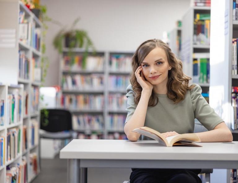 Psychologia komunikacji | Studia jednolite magisterskie w Chorzowie | Uniwersytet WSB Merito Chorzów: studentka siedząca i czytająca książkę w bibliotece