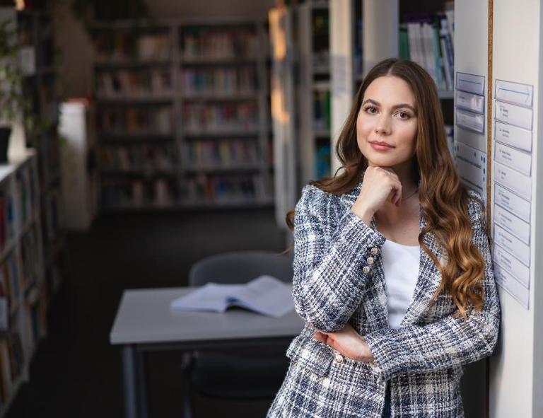 Stypendia i zniżki | Uniwersytet WSB Merito Chorzów: Studentka stojąca w bibliotece 