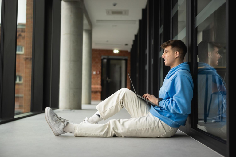 Digital university | WSB Merito Poznań University: Poznań - student w korytarzu z laptopem