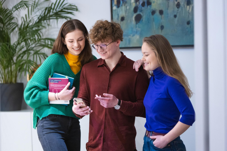 Student organisations and research clubs | WSB Merito Poznań University: Troje studentów z uśmiechem przegląda telefon.
