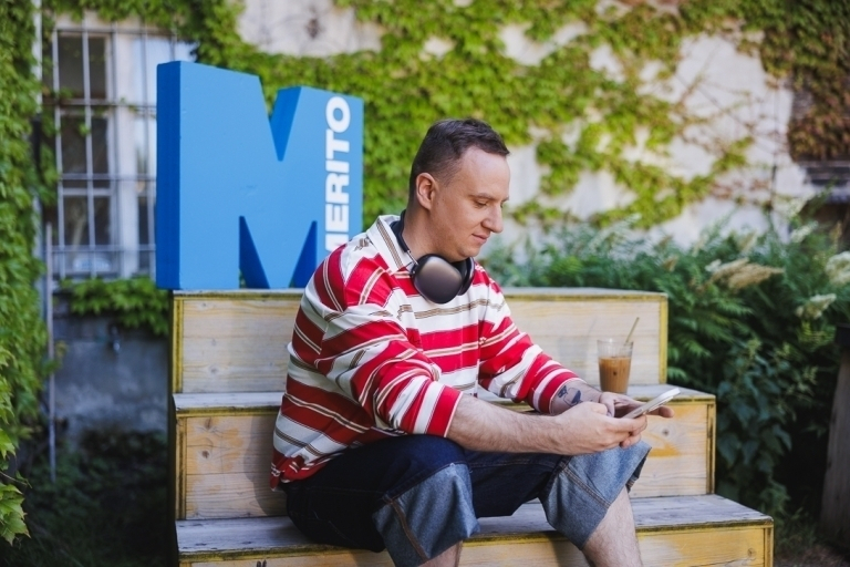 Student leaning against Merito logo