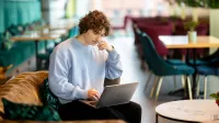 Inżynieria zarządzania innowacjami technologicznym | Studia I stopnia w Gdańsku | Uniwersytet WSB Merito w Gdańsku: Student siedzi na kanapie w kawiarni i pracuje na laptopie