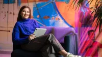 Grafika cyfrowa i kreacje multimedialne | Studia II stopnia ze studiami podyplomowymi  | Uniwersytet WSB Merito w Gdańsku: Studentka siedzi w fotelu z tabletem w kolorowej strefie studenta