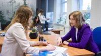 Zarządzanie w administracji publicznej | Studia II stopnia ze studiami podyplomowymi  | Uniwersytet WSB Merito w Gdańsku: Rozmowa przy biurku dwóch kobiet ubranych biznesowo