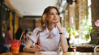 Zarządzanie zasobami ludzkimi – z certyfikatem FU | Studia II stopnia ze studiami podyplomowymi  | Uniwersytet WSB Merito w Gdańsku: Studentka notuje coś w zeszycie w kawiarni przy soku