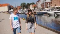 Transport morski i lotniczy | Studia II stopnia ze studiami podyplomowymi  | Uniwersytet WSB Merito w Gdańsku: Studenci idą przez gdańską marinę