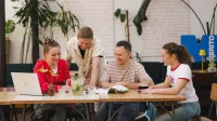 Zarządzanie | Studia II stopnia ze studiami podyplomowymi w Gdańsku | Uniwersytet WSB Merito w Gdańsku: Studenci przy stoliku w kawiarni. Wspólnie pracują nad projektem przy laptopie
