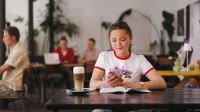 Marketing i sprzedaż | Studia II stopnia ze studiami podyplomowymi w Gdańsku | Uniwersytet WSB Merito w Gdańsku: Studentka w kawiarni z kawą i przy otwartej książce