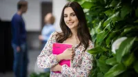 Psychologia zdrowia | Studia jednolite magisterskie w Gdańsku | Uniwersytet WSB Merito w Gdańsku: Studentka przy zielonej ścianie z książką w ręku