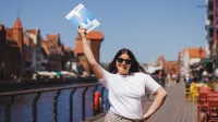 Finanse przedsiębiorstw i podatki z certyfikatem ACCA | Studia II stopnia ze studiami podyplomowymi  | Uniwersytet WSB Merito w Gdańsku: Studentka z teczką z sygnetem M, z tyłu widać Gdańskiego Żurawia