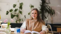 Copywriting | Studia II stopnia w Gdańsku | Uniwersytet WSB Merito w Gdańsku: Studentka w kawiarni z książką i kubkiem z literą M