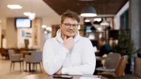 Literatura współczesna i kultura krajów anglojęzycznych | Studia II stopnia w Gdańsku | Uniwersytet WSB Merito w Gdańsku: Student w białej bluzie w holu przy stoliku 