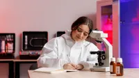 Kryminalistyka i kryminologia | Studia I stopnia w Gdańsku | Uniwersytet WSB Merito w Gdańsku: Studentka spisuje obserwacje po oglądaniu dowodu pod mikroskopem