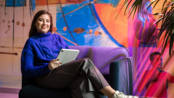 Grafika cyfrowa i kreacje multimedialne | Studia II stopnia ze studiami podyplomowymi  | Uniwersytet WSB Merito w Gdańsku: Studentka siedzi w fotelu z tabletem w kolorowej strefie studenta
