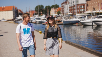 Transport morski i lotniczy | Studia II stopnia ze studiami podyplomowymi  | Uniwersytet WSB Merito w Gdańsku: Studenci idą przez gdańską marinę