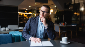 Projektowanie interfejsów graficznych | Studia podyplomowe w Gdańsku | Uniwersytet WSB Merito w Gdańsku: Mężczyzna w ubraniu biznesowym siedzi przy biurku z filiżanką kawy
