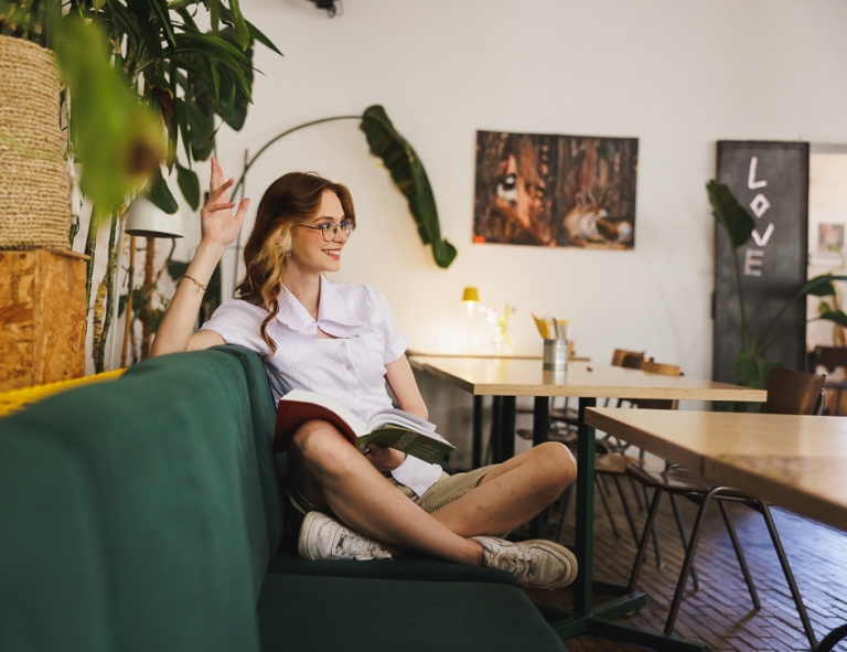 Terapia pedagogiczna z elementami integracji sensorycznej | Studia II stopnia w Gdańsku | Uniwersytet WSB Merito w Gdańsku: Studentka w restauracji z książką na kolanach w wygodnej pozie