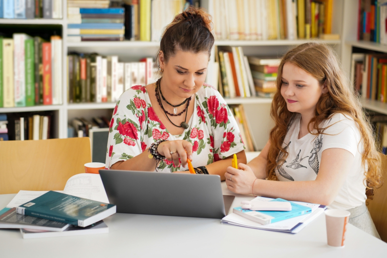 Pedagogika | Studia II stopnia w Gdańsku | Uniwersytet WSB Merito w Gdańsku: Zdjęcie kobiety pokazującej coś w laptopie młodej dziewczynce