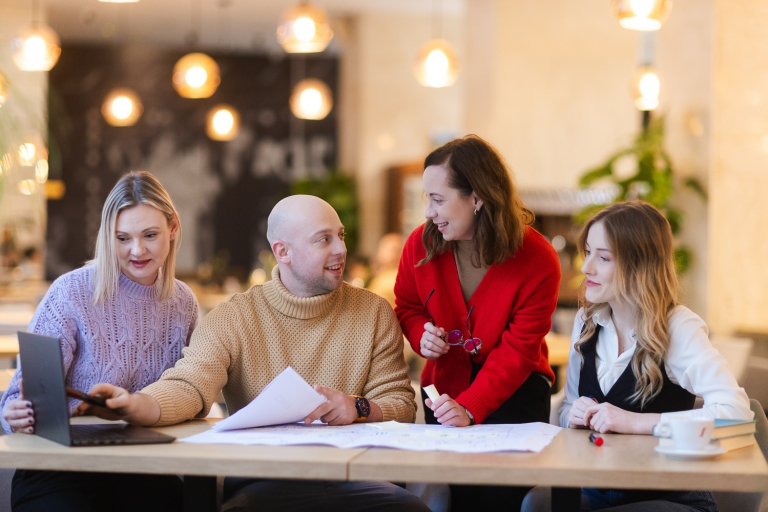 Psychologia reklamy i komunikacji | Studia podyplomowe w Gdańsku | Uniwersytet WSB Merito w Gdańsku: Studenci pracują w grupie w przestrzeni o ciepłym pomarańczowym świetle