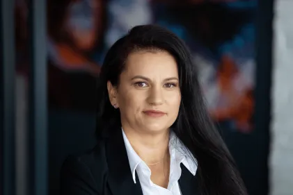 Władze uniwersytetu | Uniwersytet WSB Merito w Gdańsku: Portret kobiety w średnim wieku o ciemnych, długich włosach. Jest ona w ciemnej marynarce i białej koszuli. Lekko się uśmiecha