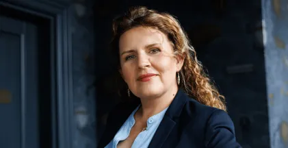 Władze uniwersytetu | Uniwersytet WSB Merito w Gdańsku: Uśmiechająca się kobieta w lokach i niebieskiej koszuli