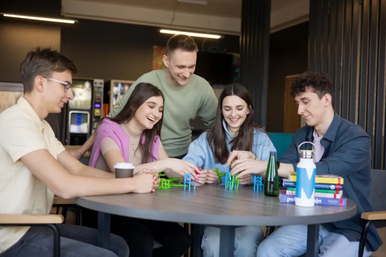 Terapia pedagogiczna z elementami integracji sensorycznej | Studia II stopnia w Gdańsku | Uniwersytet WSB Merito w Gdańsku: Studenci siedzą na przerwie i układają konstrukcję z zabawkowych krzesełek