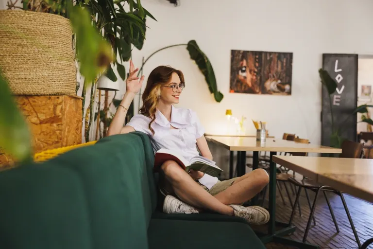 Specjalista kadr i płac z elementami technik coachingu | Studia II stopnia w Gdańsku | Uniwersytet WSB Merito w Gdańsku: Studentka w restauracji z książką na kolanach w wygodnej pozie