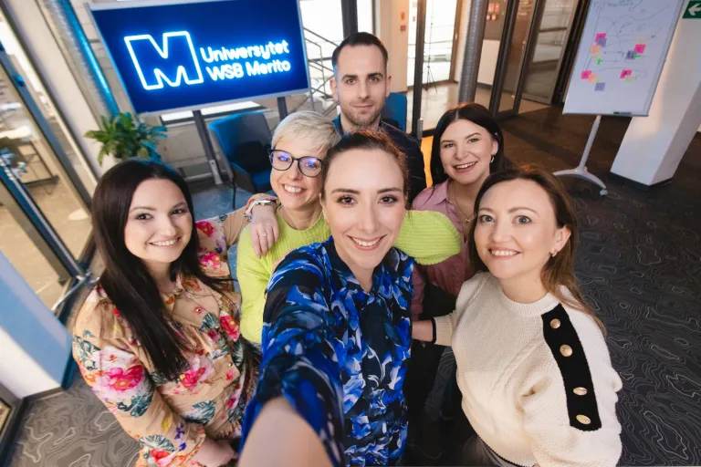 Weź udział w sesji zdjęciowej i zostań twarzą Uniwersytetu! | Aktualności | Uniwersytet WSB Merito w Gdańsku: Selfie słuchaczy studiów podyplomowych przy neonowym sygnecie Merito