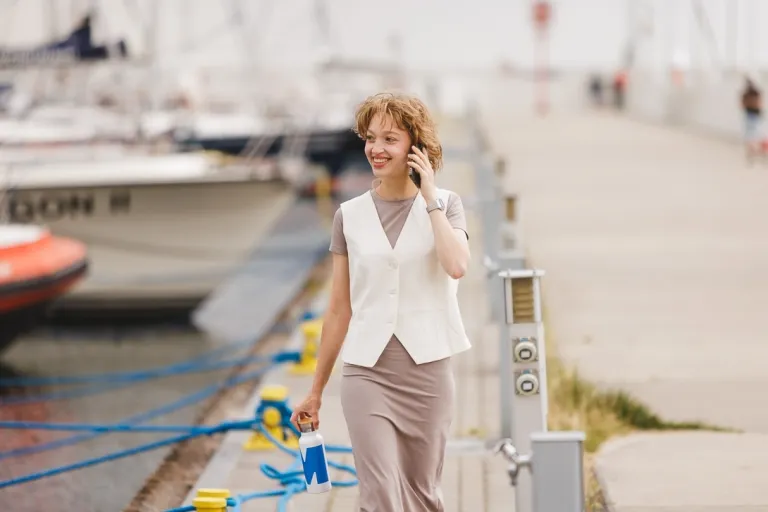 Kadry i płace | Studia I stopnia w Gdańsku | Uniwersytet WSB Merito w Gdańsku: Studentka rozmawia przez telefon idąc przez gdyńską marinę