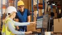 Transport Spedycja Logistyka | Studia I stopnia w Gdyni | Uniwersytet WSB Merito Gdynia: pracownicy w kaskach w magazynie przy komputerze
