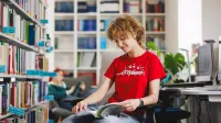 Finanse i rachunkowość | Studia I stopnia w Gdyni | Uniwersytet WSB Merito Gdynia: Studentka w bibliotece przegląda książkę 
