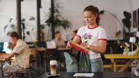 Bezpieczeństwo systemów informatycznych | Studia I stopnia w Gdyni | Uniwersytet WSB Merito Gdynia: Studentka pakuje plecak w kawiarni