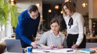 Zielone technologie i sztuczna inteligencja: informatyka dla zrównoważonego rozwoju | Studia podyplomowe w Gdyni | Uniwersytet WSB Merito Gdynia: Grupa pracująca nad zagadnieniem przy notatkach i laptopie