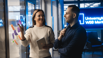 Programista Python Developer | Studia podyplomowe w Gdyni | Uniwersytet WSB Merito Gdynia: Kobieta i mężczyzna na Uniwersytecie WSB Merito podczas rozmowy biznesowej