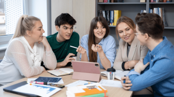 Terapia pedagogiczna z elementami arteterapii | Studia I stopnia w Gdyni | Uniwersytet WSB Merito Gdynia: studenci siedzą przy stole rozmawiając i pracując nad projektem