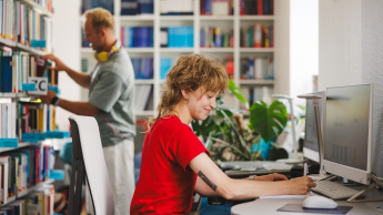 Cyberbezpieczeństwo i ochrona danych w Administracji | Studia I stopnia w Gdyni | Uniwersytet WSB Merito Gdynia: Studentka przy komputerze w bibliotece