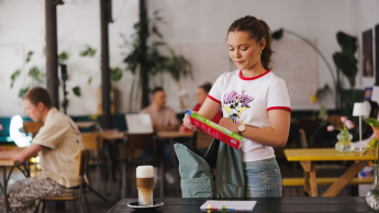 Bezpieczeństwo systemów informatycznych | Studia I stopnia w Gdyni | Uniwersytet WSB Merito Gdynia: Studentka pakuje plecak w kawiarni