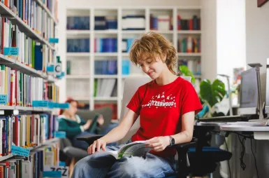 ABC studenta | Uniwersytet WSB Merito Gdynia: Studentka w bibliotece przegląda książkę 