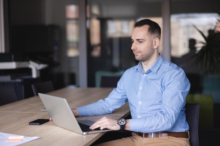 Technologie sieciowe | Studia I stopnia w Gdyni | Uniwersytet WSB Merito Gdynia: mężczyzna siedzi przy biurku i pracuje na laptopie