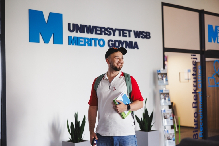 Planowanie produkcji – nowoczesne   narzędzia: SAP S/4HANA, Siemens Opcenter APS | Studia podyplomowe w Gdyni | Uniwersytet WSB Merito Gdynia: Student przed wejściem do Biura Rekrutacji