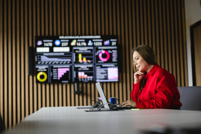 Tester oprogramowania dla aplikacji mobilnych i serwerowych z zastosowaniem AI | Studia podyplomowe w Gdyni | Uniwersytet WSB Merito Gdynia: Kobieta na spotkaniu online, w tle ekran z wykresami