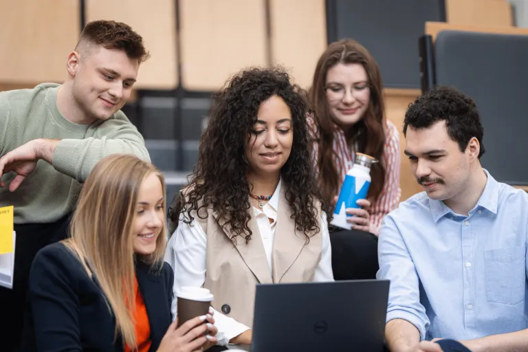 Filologia | Studia I stopnia w Gdyni | Uniwersytet WSB Merito Gdynia: Grupa studentów znajdujących się na auli i siedzących wokół siebie z laptopem