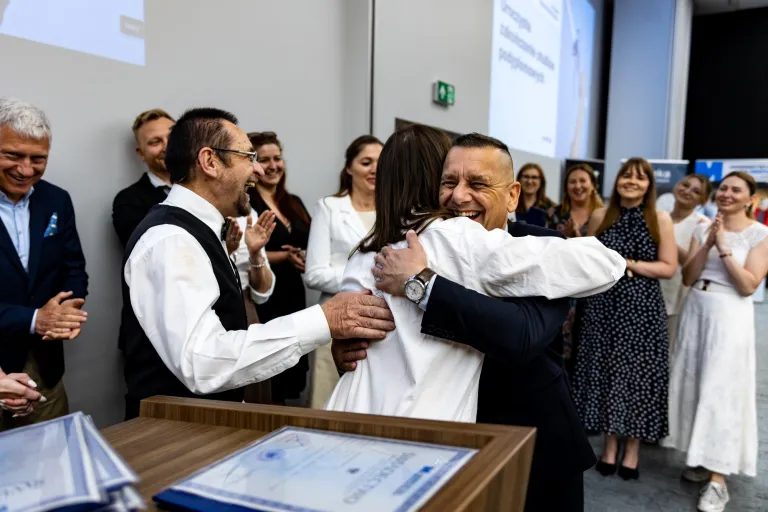 Uroczyste zakończenie studiów podyplomowych 2025/2026 za nami! | Aktualności | Uniwersytet WSB Merito Gdynia: Fotografia reporterska z wydarzenia rozdania dyplomów po ukończeniu studiów podyplomowych przedstawiająca uścisk absolwenta z opiekunem kierunku 