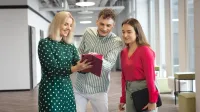 Sztuczna inteligencja w biurze | Uniwersytet WSB Merito Łódź: Uczniowie spoglądają na tablet na Uniwersytecie WSB Merito w Łodzi