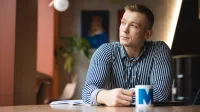 Administracja i bezpieczeństwo wewnętrzne | Uniwersytet WSB Merito Łódź: Student pije kawę w trakcie przerwy z kubka Uniwersytetu WSB Merito w Łodzi