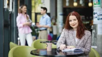 Digital marketing | Uniwersytet WSB Merito Łódź: Studentka zapisuje notatki, a obok stoi kawa.